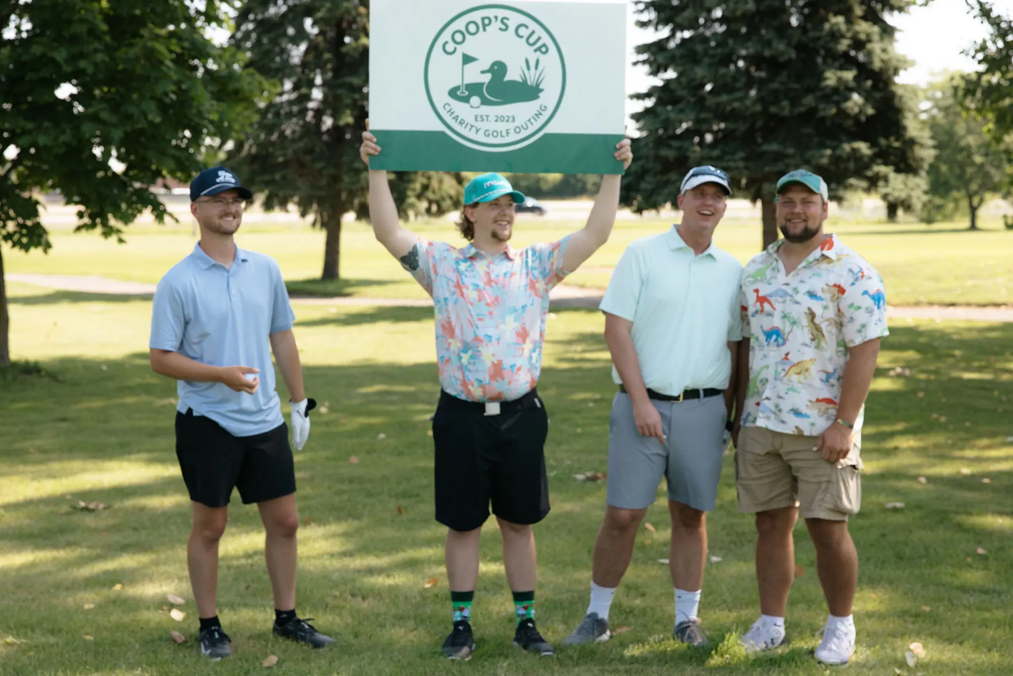 A colorful foursome poses with the Coop's Cup banner