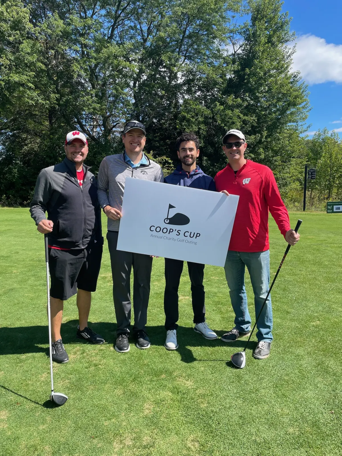 Matt Haag, Mike Haag, Austin Rickertsen, and Kiran Prasad holding the Coop's Cup sign